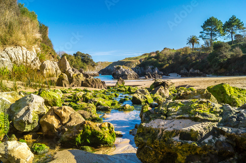 Fotografie In sunny day and blue sky, small river flows between rocks on th