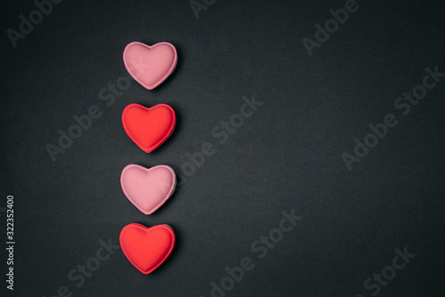 Multi-colored hearts on a black background, top view down.