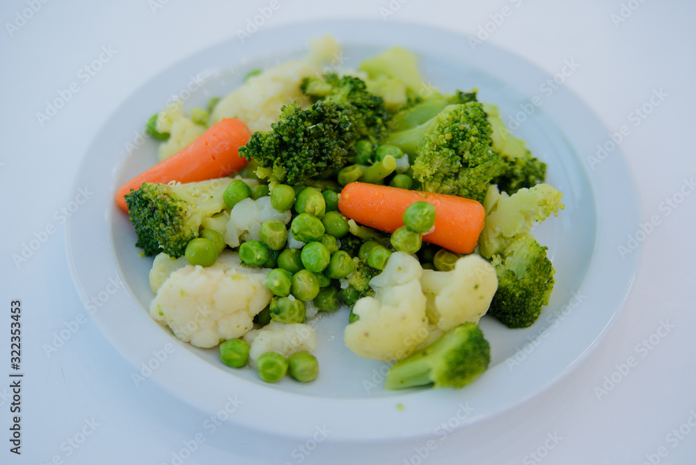 Cooked salad, carrots, peas, Brussels sprouts on a white plate Cooked salad, carrots, peas, Brussels sprouts on a white plate