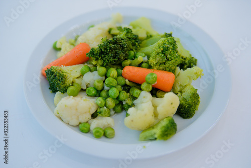 Cooked salad, carrots, peas, Brussels sprouts on a white plate