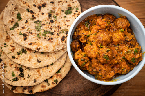 Potato curry (Kashmiri dum aloo) with chapatti (roti) served on wooden dining table. photo