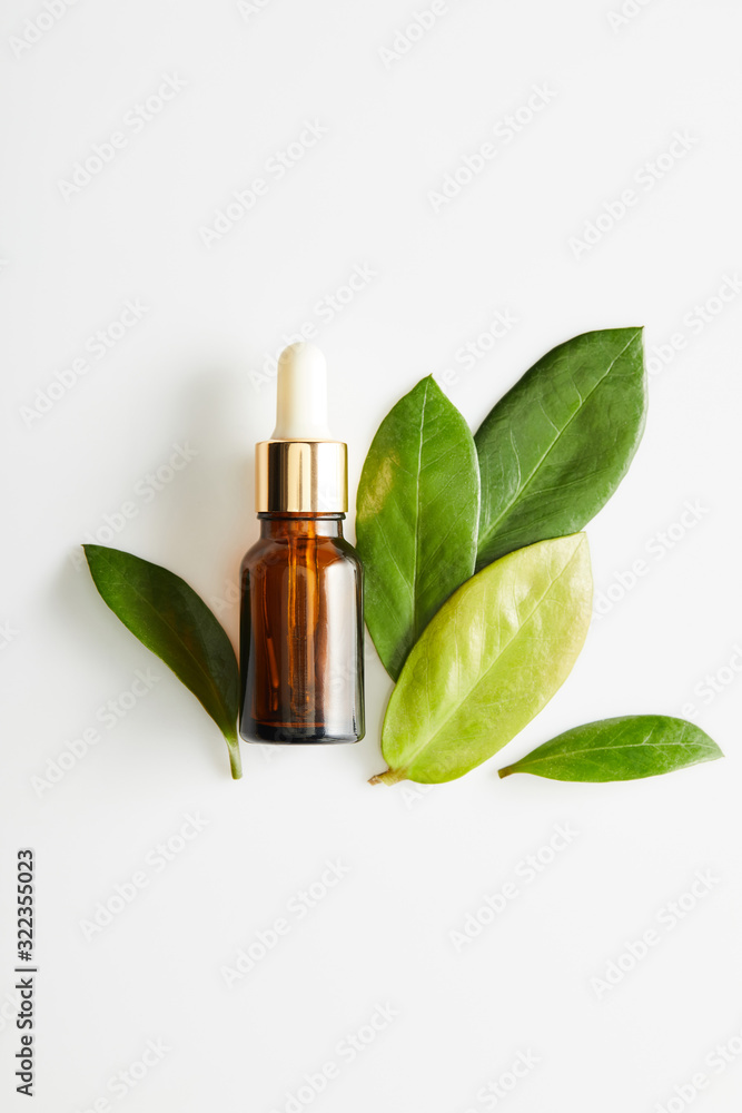 Top view of bottle of cosmetic oil with leaves on white background Top view of bottle of cosmetic oil with leaves on white background