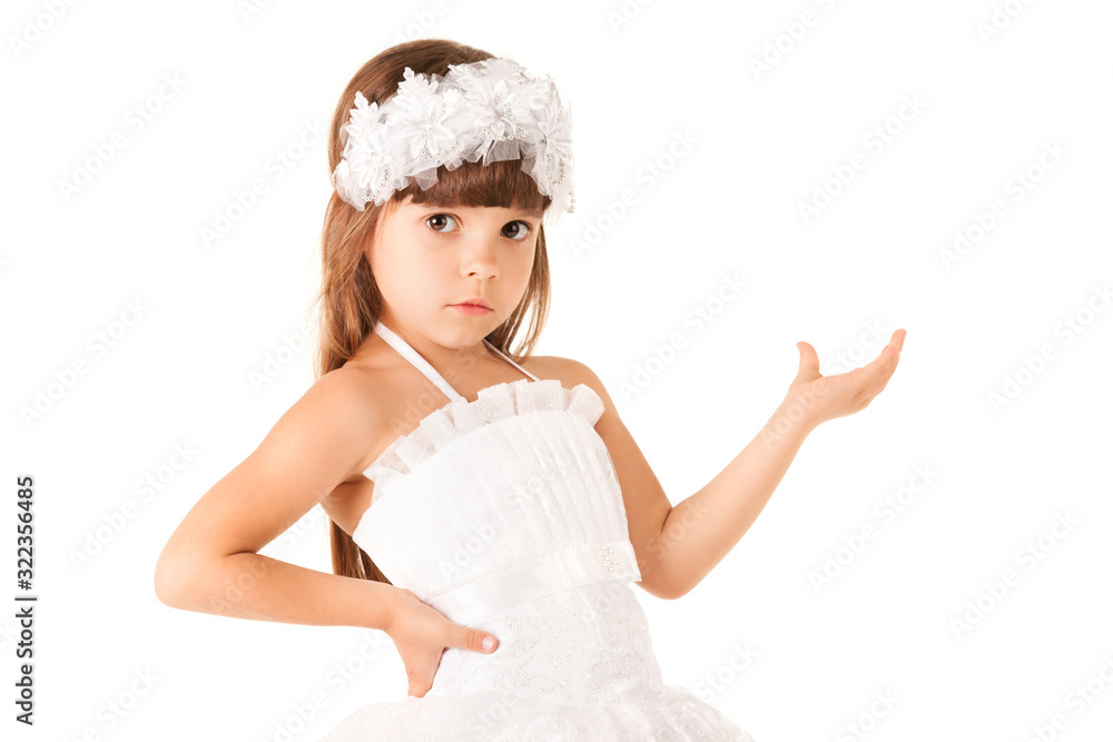 Front view of charming little girl in dress holding hand on waist and looking at camera. Adorable kid wearing beautiful flower crown. Isolated on white studio background. Concept of little princess. Front view of charming little girl in dress holding hand on waist and looking at camera. Adorable kid wearing beautiful flower crown. Isolated on white studio background. Concept of little princess.