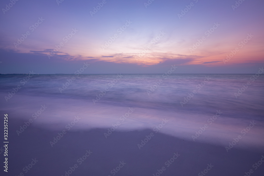 Idyllic colorful seascape - the wavy surface of the water reflects the pink and blue colors of the sky. Dramatic seascape
