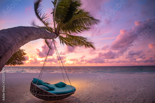 Tropical sunset beach background as summer landscape panorama with beach swing or hammock and white sand and calm sea beach banner. Perfect beach scene vacation or summer holiday concept