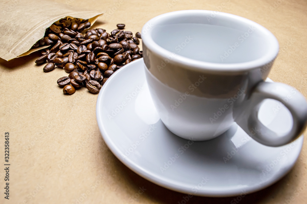 Coffee beans sprinkled from the packaging and a white cup on a beige background, Coffee beans sprinkled from the packaging and a white cup on a beige background,