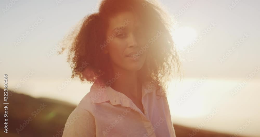 Portrait of a young attractive african american woman looking into the camera calmly and smiling at sunset Portrait of a young attractive african american woman looking into the camera calmly and smiling at sunset