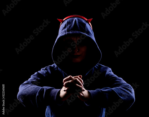 Shooting in the Studio. The girl in the hood holds her hands in front of her. Artificial horns on the head.