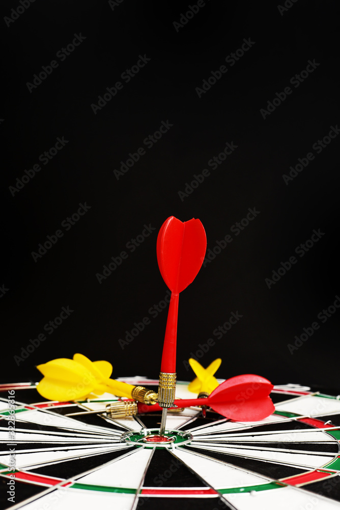 Close up Red dart arrow hitting on the center dartboard, Marketing target success or the winner, on black background Close up Red dart arrow hitting on the center dartboard, Marketing target success or the winner, on black background