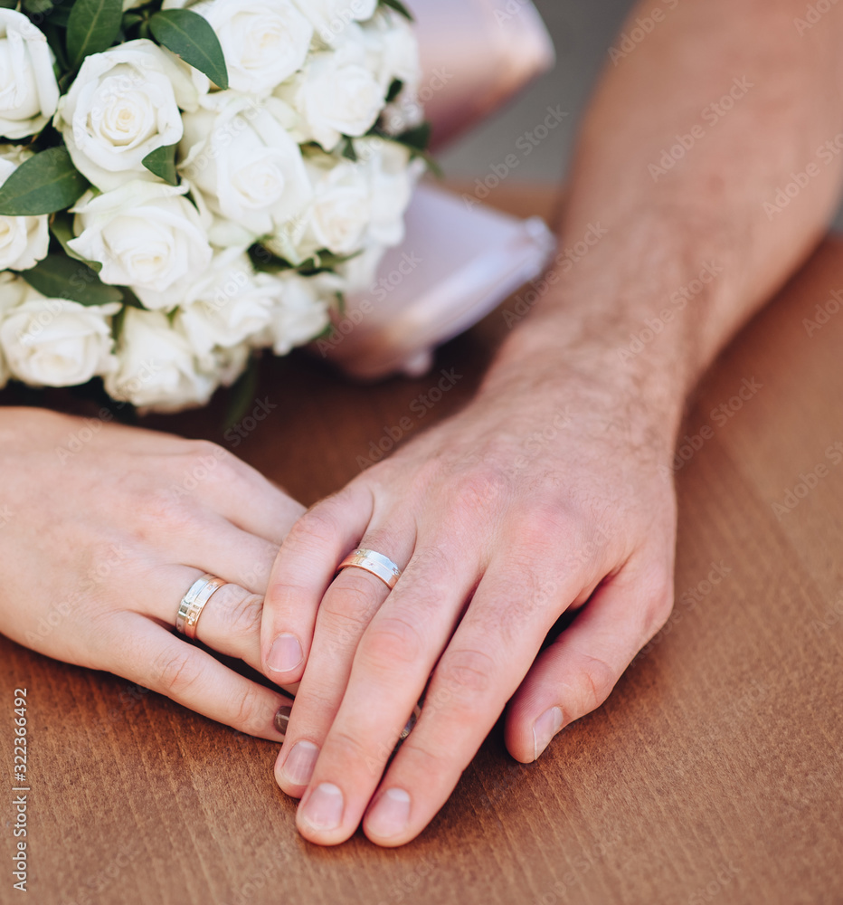 Bride and groom cute hold hands with golden rings and a bouquet of roses on a wooden table background. Photography, concept. Bride and groom cute hold hands with golden rings and a bouquet of roses on a wooden table background. Photography, concept.