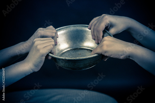 Two pairs of children's hands hold a metal plate.