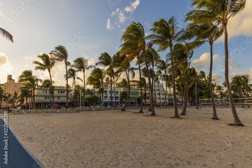 Beautiful landscape view of Miami South Beach. Buildings on one side and palm trees on another side. Blue sky and white clouds on background. 