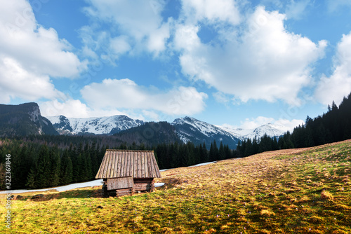 Old wooden hut and cloudy sky in spring High Tatras mountains in Kalatowki meadow, Zakopane, Poland. Landscape photography photo