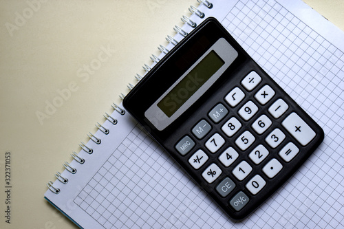 White notebook and digital calculator on a white table, isolate