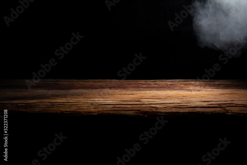 table top made of old wood with a spot of light and blue smoke in dark colors