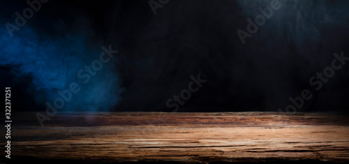 table top made of old wood with a spot of light and blue smoke in dark colors