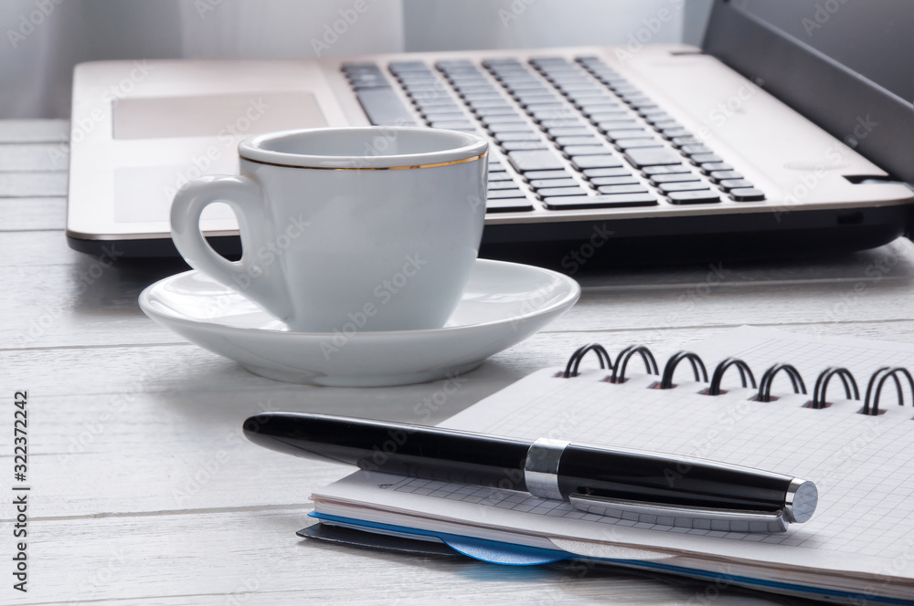 Cup of coffee, laptop and notebook with pen on desktop Cup of coffee, laptop and notebook with pen on desktop