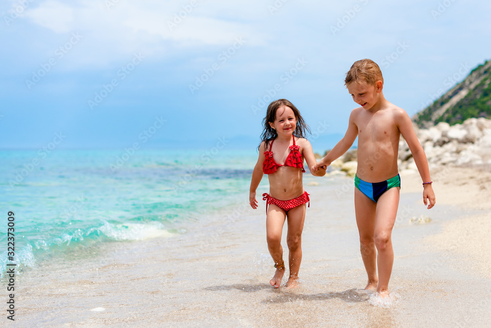 Siblings are smiling and walking on the beach