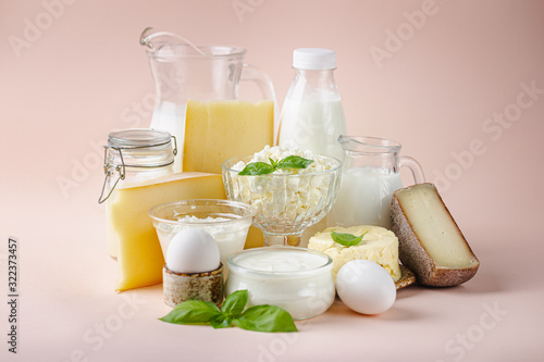 Fresh dairy products, milk, cottage cheese, eggs, yogurt, sour cream and butter on pink background