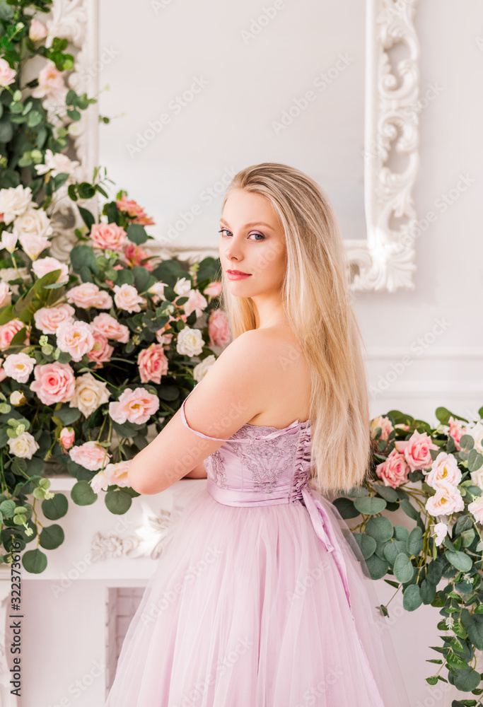 Beautiful romantic young woman with natural makeup posing against a background of flowers. The girl is blonde with a clean look and a beautiful smile.Close-up portrait. Perfume and cosmetic concept Beautiful romantic young woman with natural makeup posing against a background of flowers. The girl is blonde with a clean look and a beautiful smile.Close-up portrait. Perfume and cosmetic concept