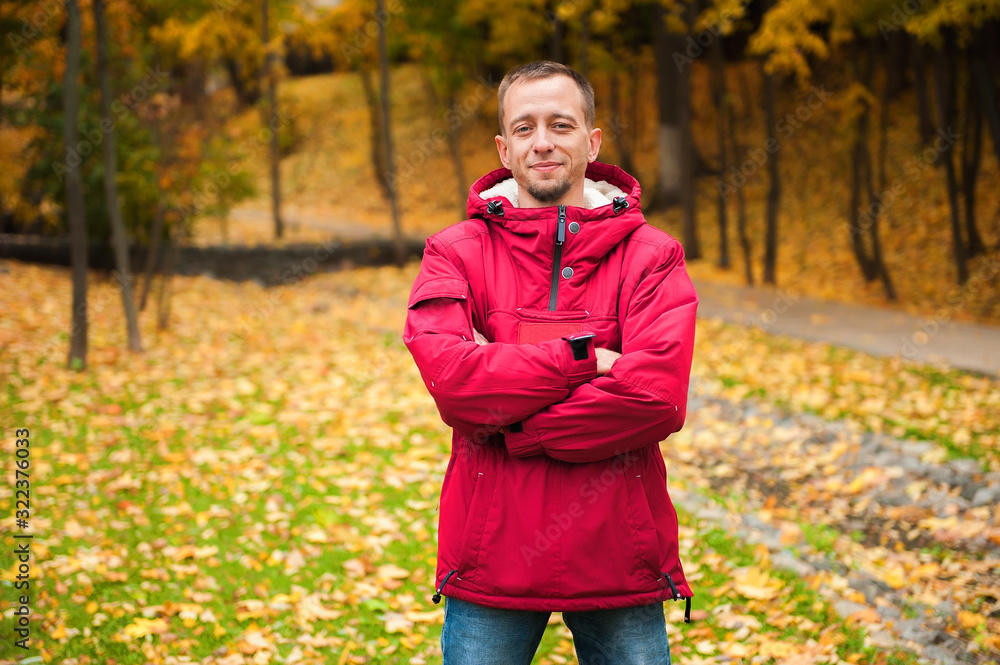 a man in a red jacket anorak stands against the backdrop of an autumn forest a man in a red jacket anorak stands against the backdrop of an autumn forest