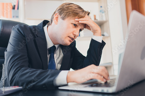 Depressed stress Caucasian businessman touch his forehead while looking at the laptop nearly cry and upset, concept failure of the business, upset stressed businessman, frustration business concept