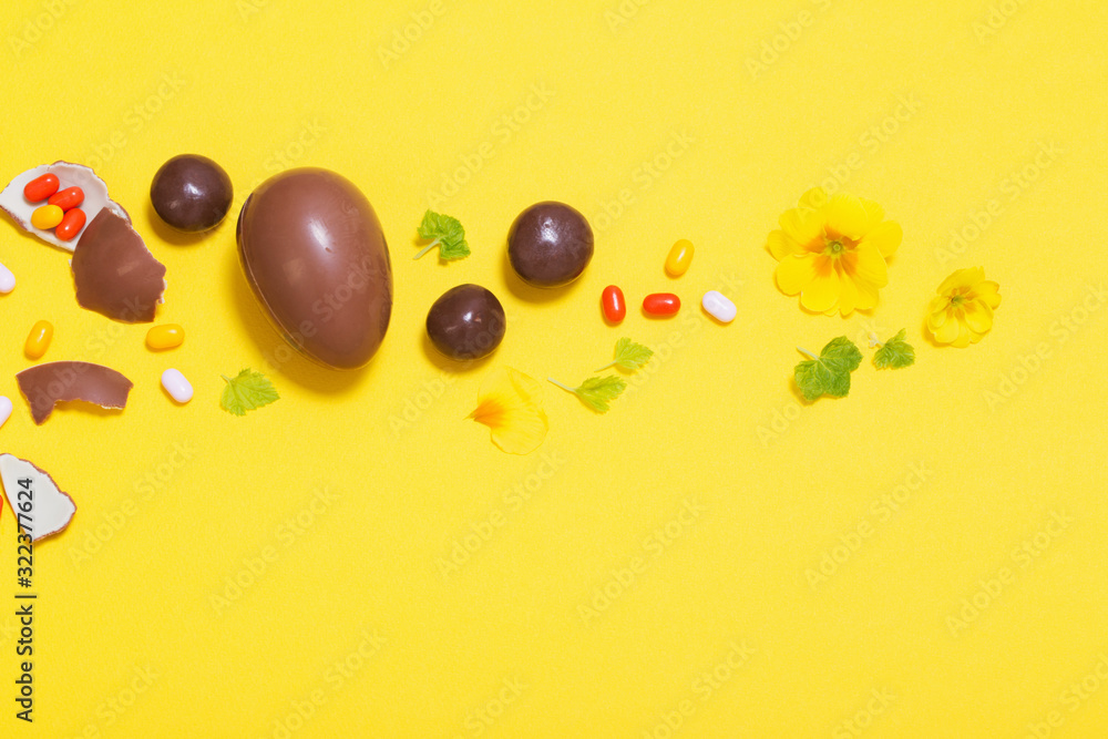 Easter yellow background with chocolatte eggs, candy and spri Easter yellow background with chocolatte eggs, candy and spri