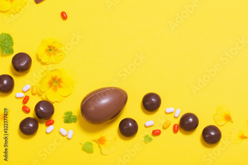 Easter yellow background with chocolatte eggs     candy and spri