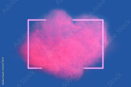 Pink neon powder explosion with gliwing frame on blue background. Colored cloud. Colorful dust explode. Paint Holi.