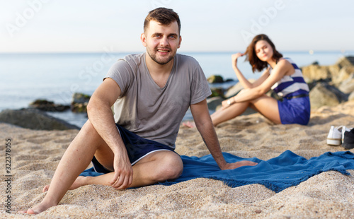 Man sitting on the beach. Girl on the background