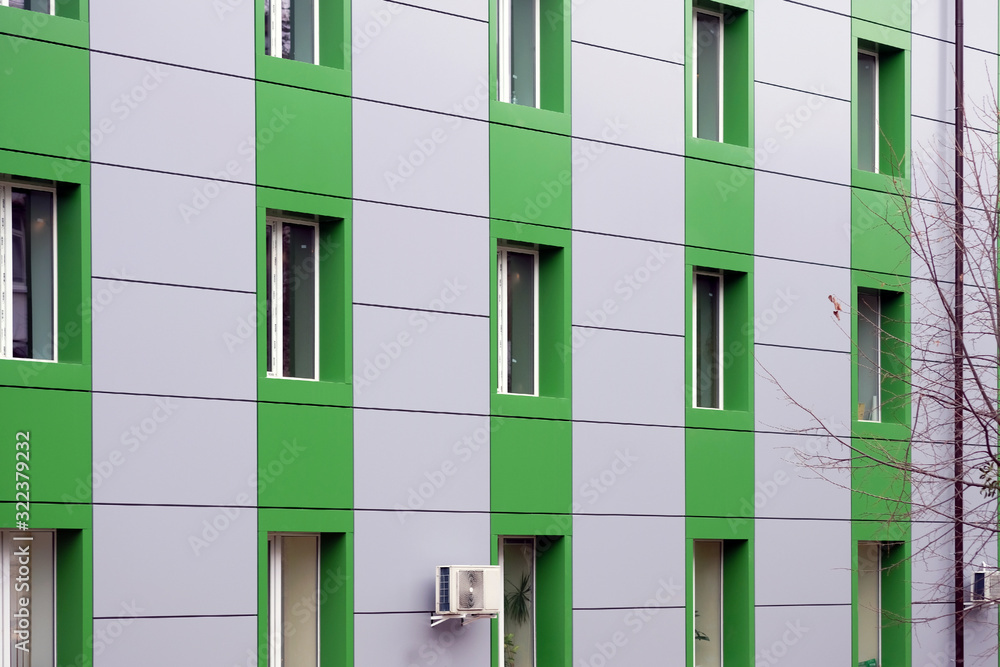 Decorative facade finish of the house. Facing panel in gray and green for the wall of a multi-story building. Wall of an apartment building with windows and air conditioning. Decorative facade finish of the house. Facing panel in gray and green for the wall of a multi-story building. Wall of an apartment building with windows and air conditioning.
