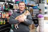 Portrait of adult man with dog in petshop, boy on background