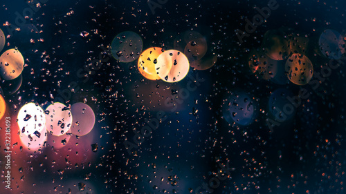 Rain drops on the window; blured bokeh lights on background; selective focus