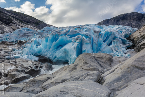 Melting blue glacier with water flowing away in Laerdal, Norway. Nigardsbreen glacier, a part of the large Jostedalsbreen glacier.