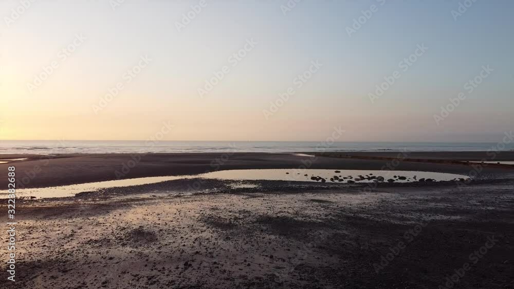 Sunset beach drone shot, a beautiful ocean landscape, waves coming in on the sandy shoreline, the sky is illuminated by the pretty sun Sunset beach drone shot, a beautiful ocean landscape, waves coming in on the sandy shoreline, the sky is illuminated by the pretty sun
