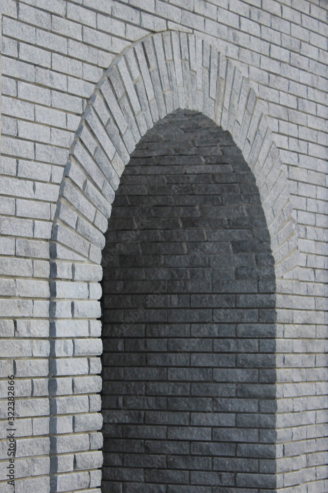 Brick gray wall with a semicircular arch entrance.