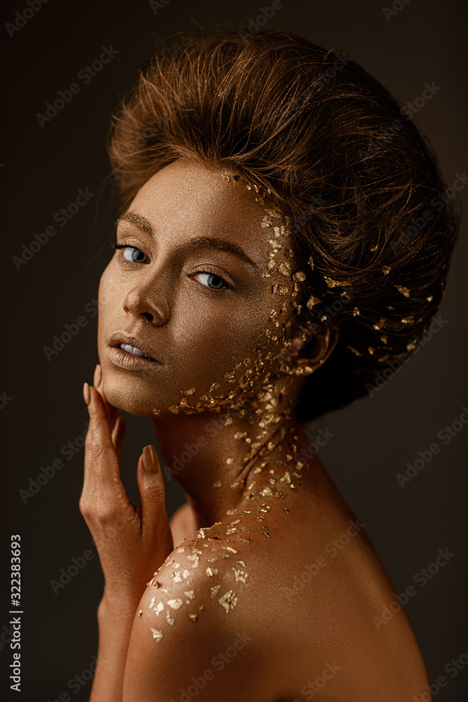 Fototapeta Moda sztuka portret model dziewczyna z wakacje złoty błyszczący profesjonalny makijaż. beaty kobieta ze złotym metalicznym ciałem i włosami na ciemnym tle. Złota świecąca skóra.