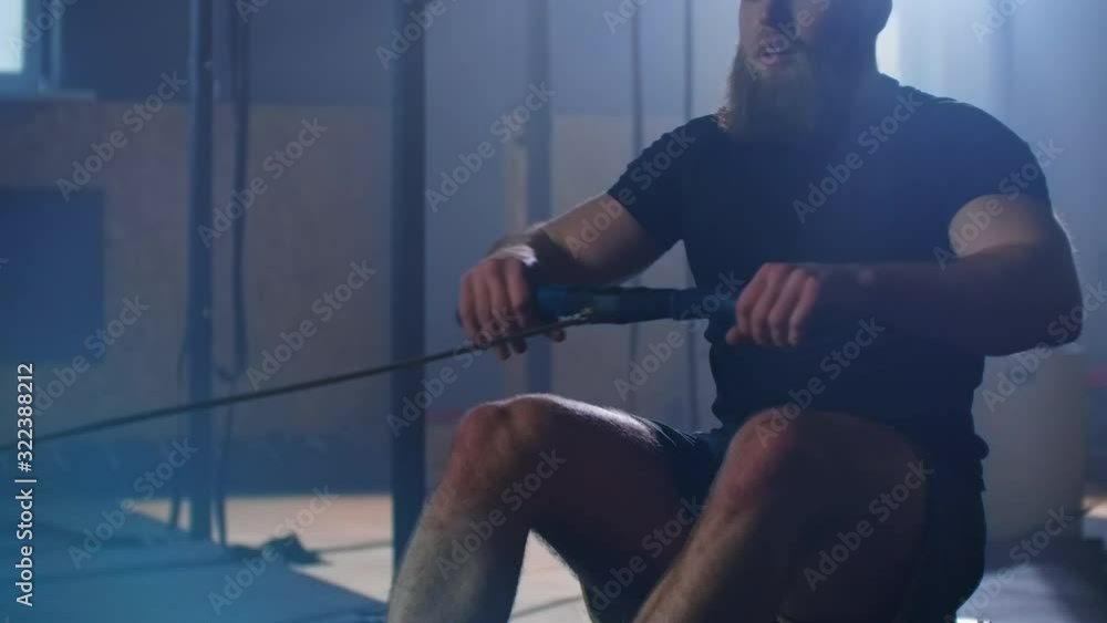 Slow motion: fitness man athlete training rowing machine exercise intense endurance workout challenge strong sportsman physical practice in gym healthy lifestyle motivation Slow motion: fitness man athlete training rowing machine exercise intense endurance workout challenge strong sportsman physical practice in gym healthy lifestyle motivation