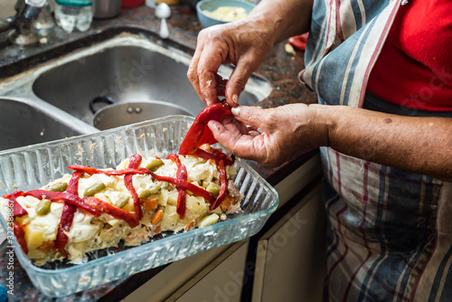 older woman preparing russian salad with mayonnaise potatoes bell peppers and olives