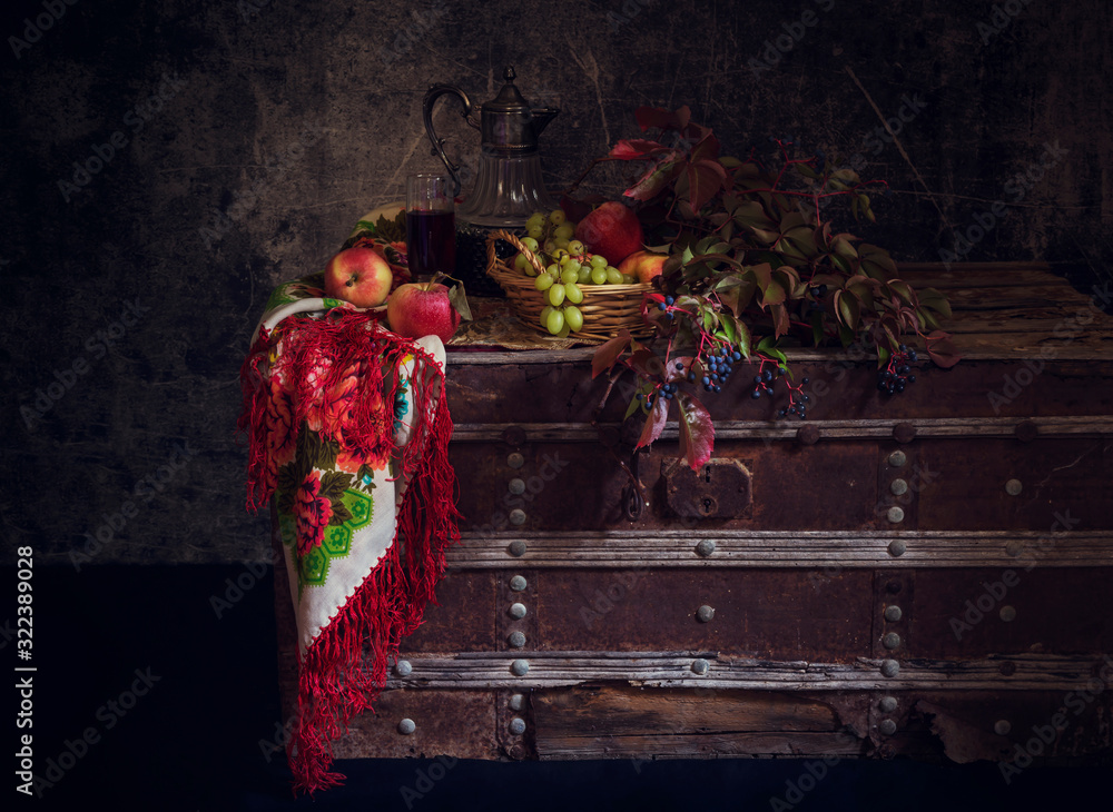 Obraz premium Still life with wine in a jug and a glass, grapes and apples, shawl and branches of wild grapes