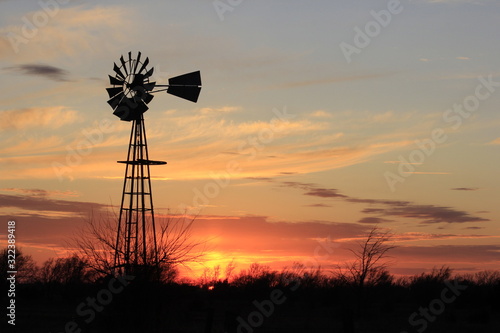 Kansas colorful Sunset with cloud's,tree's and a Windmill silhouette out in the country.