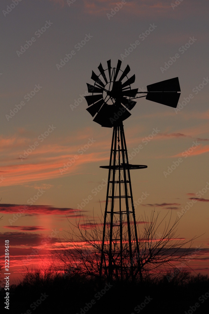 Kansas colorful Sunset with cloud's,tree's and a Windmill silhouette out in the country. Kansas colorful Sunset with cloud's,tree's and a Windmill silhouette out in the country.