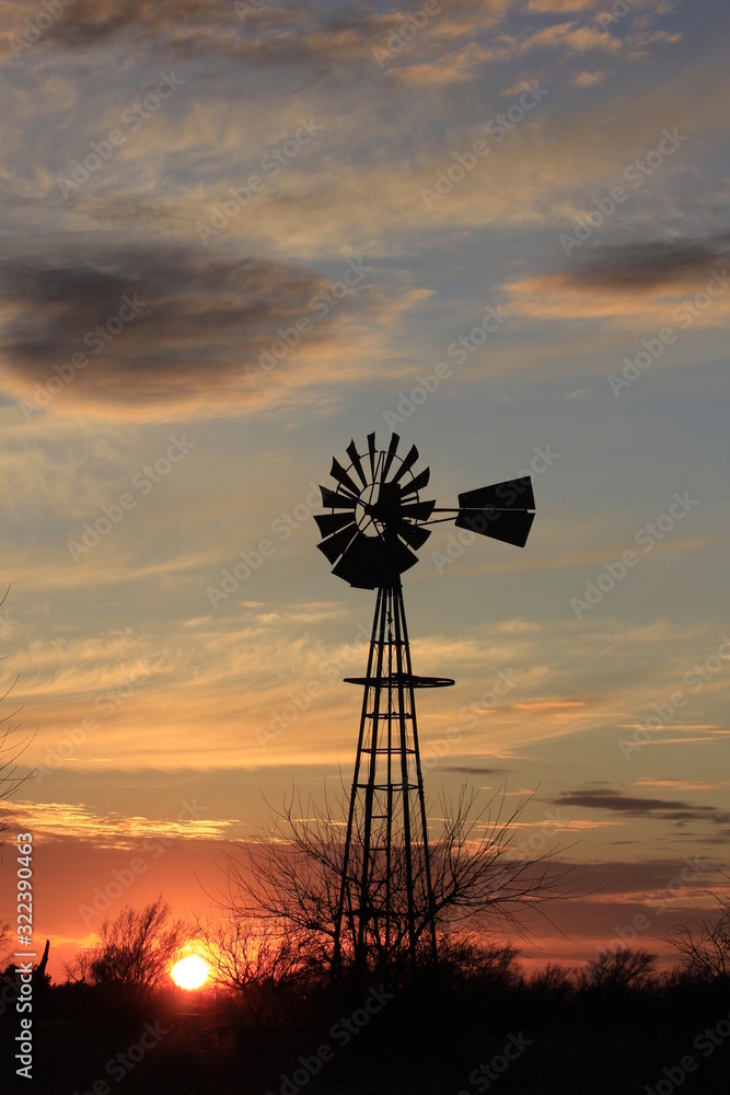 Kansas colorful Sunset with cloud's,tree's and a Windmill silhouette out in the country.