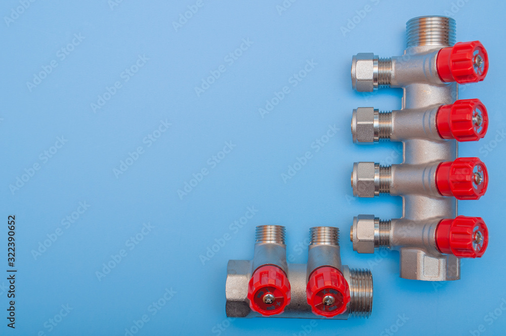 A steel supply manifold with red regulators on a blue background. A steel supply manifold with red regulators on a blue background.