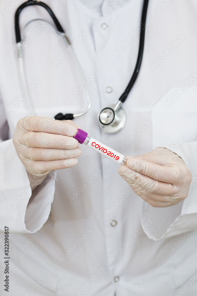 a doctor in a white coat, with a phonendoscope around her neck and gloves, holds a positive blood test for coronavirus COVID-2019. test tube with virus analysis a doctor in a white coat, with a phonendoscope around her neck and gloves, holds a positive blood test for coronavirus COVID-2019. test tube with virus analysis