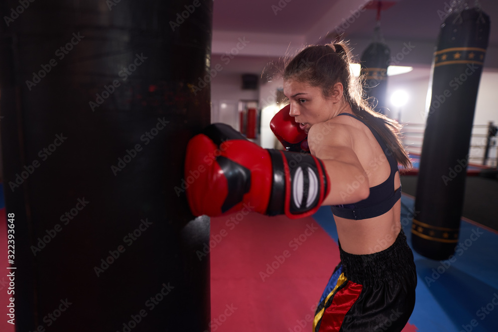 Kickboxer female working with heavy bag