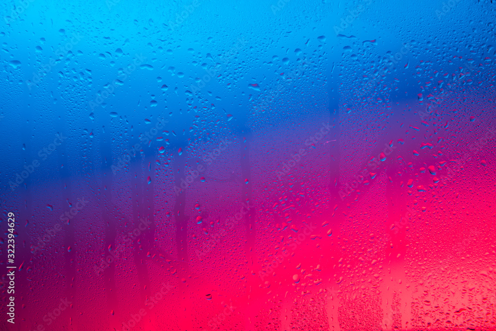 Glass with water drops on colorful background.