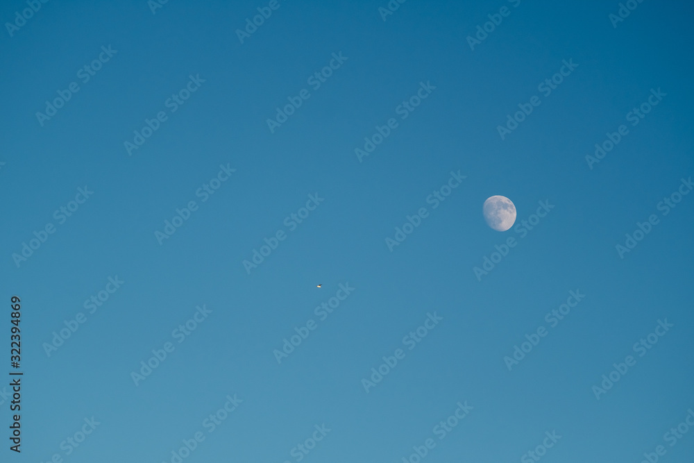 White moon against the blue sky. Full moon in the afternoon. Satellite of the planet earth. Blue skies on a frosty winter day. White moon against the blue sky. Full moon in the afternoon. Satellite of the planet earth. Blue skies on a frosty winter day.