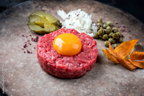 Gourmet Tartar roh vom Filet vom Rind mit Eigelb, Gurken und Gemüse Chips als closeup auf einem Modern Design Teller photo