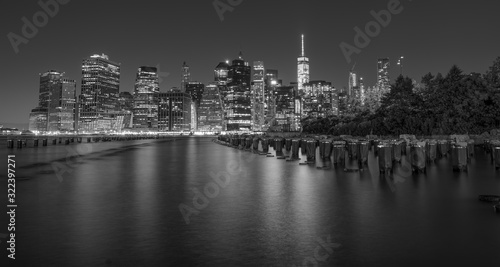 Dramatic, black and white New York City skyline from Brooklyn Bridge Park at night.